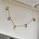 Gold necklace with various pendants on a light background