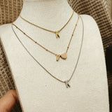 Gold necklaces with letter pendants on a mannequin bust.
