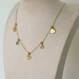 Gold necklace with various pendants on a mannequin bust against a plain background